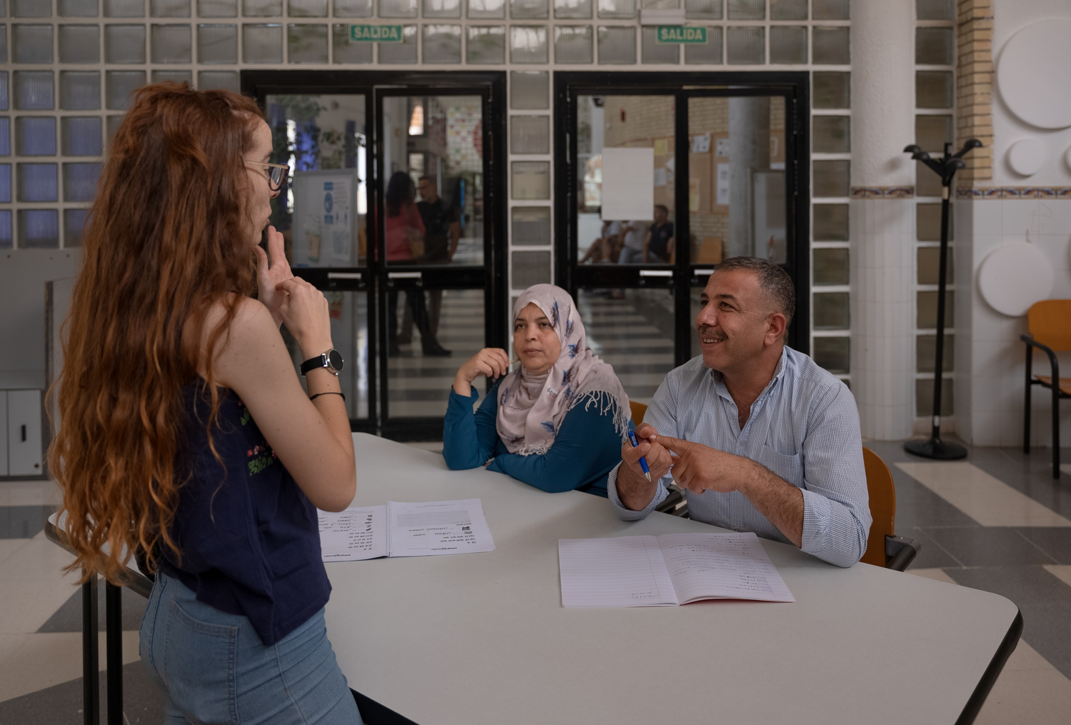 Un couple assis à une table interagit avec son professeur debout devant lui