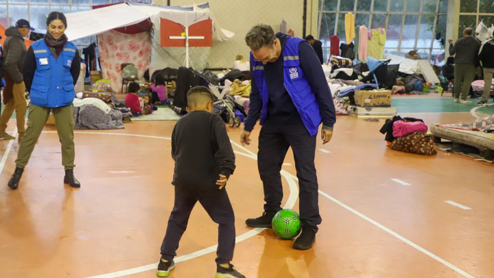 Funcionário do ACNUR joga bola com criança em abrigo emergencial